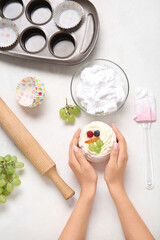 Female confectioner with tasty cake and ingredients on white background