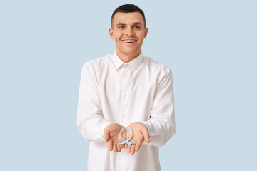Handsome man with blue ribbon on color background. Prostate cancer concept