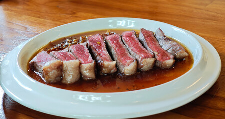 Sliced ​​rib eye steak on white plate, medium rare.