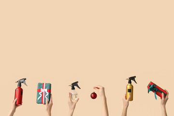 Hands holding bottles of hair spray and Christmas decorations on beige background