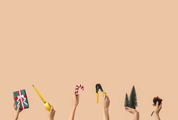 Hands holding construction tools and Christmas decorations on beige background