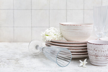 Beautiful tableware with flowers on grunge table near white tile wall