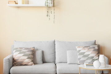 Stylish interior of light living room with cozy couch and shelf