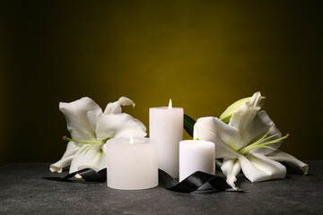 Candles and funeral flowers on dark background