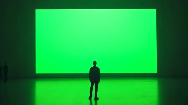 Large green screen with people observing.