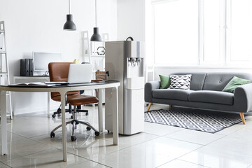 Interior of modern office with workplace, sofa and water cooler