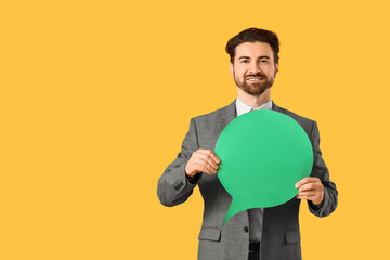 Young businessman with blank speech bubble on yellow background