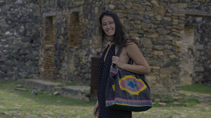 A beautiful woman with a beach bag in front of the ruins of a naval fort.