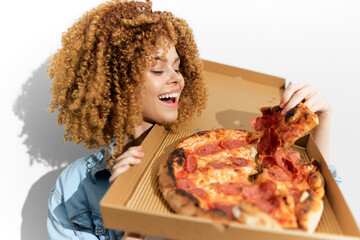 Happy woman holding a pizza box with a delicious pepperoni pizza, showcasing her joyful expression and curly hair, perfect for food lovers and pizza enthusiasts