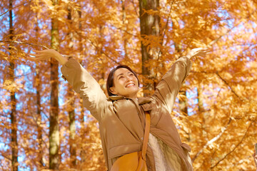 秋の紅葉の中をで深呼吸をする女性　ミドルエイジ