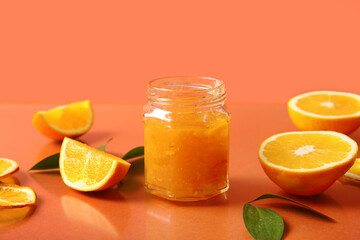 Jar of tasty orange jam on red background