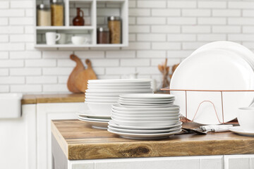 Holder with clean white plates and cutlery on counter in kitchen