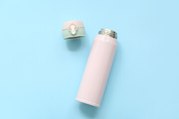 Modern pink thermos on blue background