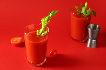 Glasses of bloody mary with celery, tomatoes and measuring cup on red background
