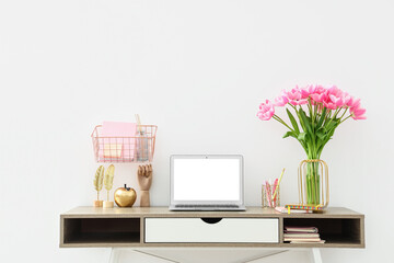 Beautiful bouquet of tulip flowers with laptop and stationery on table at workplace