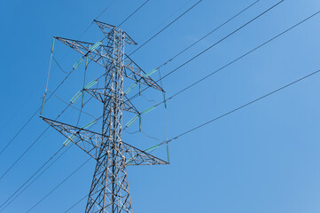 A transmission tower against blue sky. Transmission towers (electrical pylons) carry large amounts of high-voltage current over long distances.