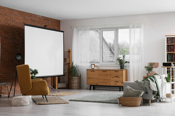 Interior of room with blank projector screen, armchair and sofa