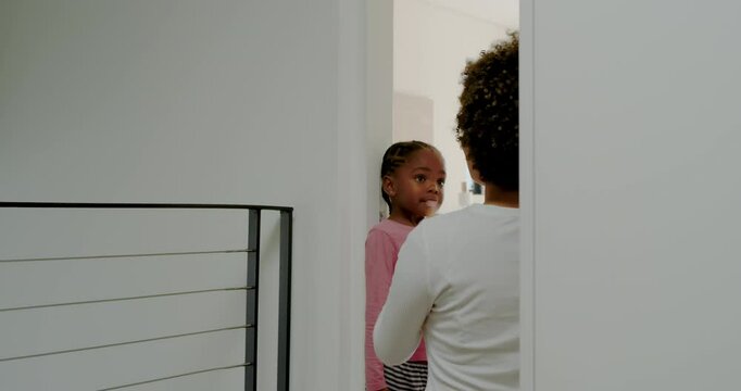 Entering hallway, mother and daughter marking height on doorframe with ruler and pencil for growth