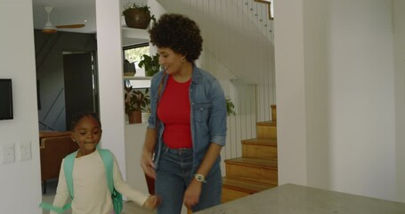 Diverse mother and daughter unpacking backpack in kitchen getting juice reviewing homework - Powered by Adobe