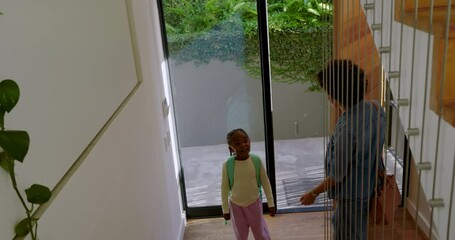 Diverse mother and daughter entering home unzipping backpack and taking juice from fridge for snack - Powered by Adobe