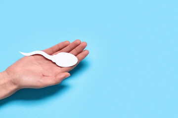Hand with sperm cell on blue background