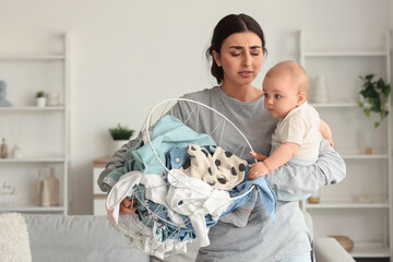 Young mother suffering from postnatal depression with her baby and laundry basket at home