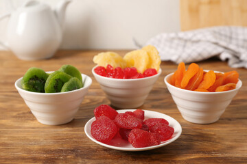 Bowls with different dried fruits on wooden table, closeup