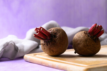 Fresh beetroot on cutting wooden board with purple background