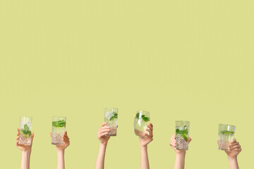 Female hands with glasses of mojito on green background