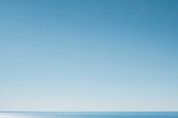 Clear, bright azure sky meeting a tranquil, flat expanse of blue ocean