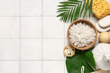 Obraz na płótnie Canvas Composition with bowl of sea salt, spa accessories and palm leaves on light tile background