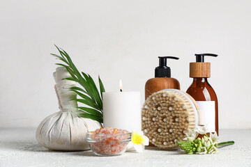 Composition with cosmetic products, spa accessories and burning candle on light table