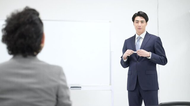 ホワイトボードを前に説明する先生・講師などの会議のプレゼンするセミナーやマーケティングのイメージの動画