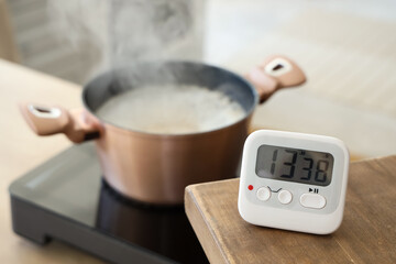 Fototapeta na wymiar Modern kitchen timer on table against cooking pot in room, closeup