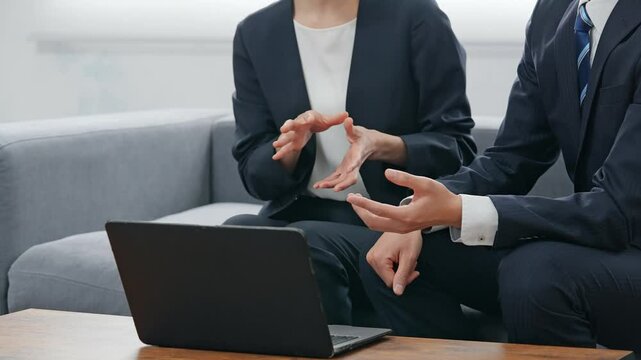 ロビーでノートパソコンを見ながら会話する男女ビジネスパーソンのグループ