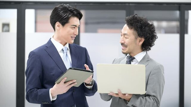 Video of two businessmen in suits having a standing meeting.