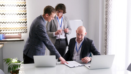 A group of men discusses the details of the contract. One of the men points to something on the paper in front of him