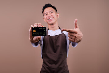 Happy Young Barista Male Showing And Pointing Credit Card For Easy Payment Method