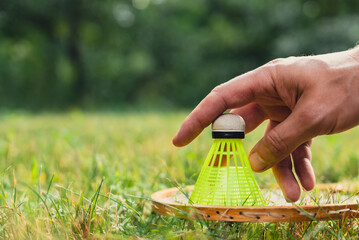 Badminton racket and shuttlecock lie on green grass. Outside recreation and fresh air. Healthy...
