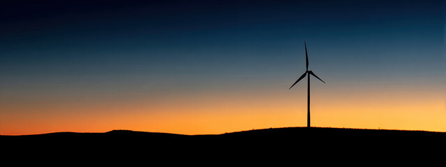 Obraz premium Wind turbine silhouette against vibrant sunset sky evokes sense of tranquility