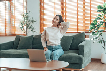 Office syndrome concept. Young asian woman feeling pain in neck and shoulder after working on computer laptop for a long time. She stretches to relax her muscles