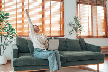Funny euphoric young asian woman celebrating winning or getting ecommerce shopping offer on computer laptop. Excited happy girl winner looking at notebook celebrating success