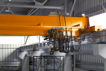 Overhead crane in factory or warehouse. Industrial machine or lifting equipment with hoist, hook and wire rope on beam girder structure for manufacturing production and freight shipping transport.