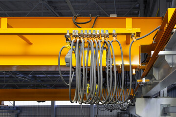 Overhead crane in factory or warehouse. Industrial machine or lifting equipment with hoist, hook and wire rope on beam girder structure for manufacturing production and freight shipping transport.