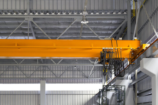 Overhead crane inside factory or warehouse building. Industrial machine or lifting equipment consist of hoist, hook and wire rope move on beam girder structure for manufacturing production plant.