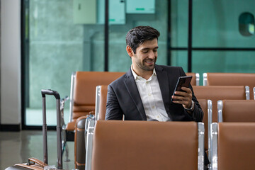 Caucasian businessman is using smart mobile phone while waiting in airline business departure lounge waiting for boarding airplane concept
