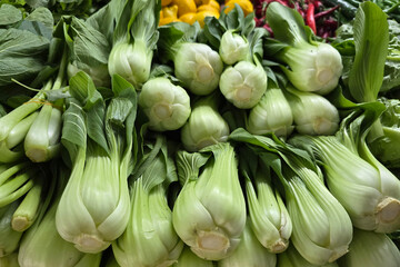 Close-up view of fresh bok choy neatly arranged at a vegetable stall in a traditional Asian farmer's market.