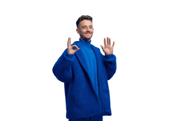 A man in a blue jacket is smiling and making a peace sign with his hands