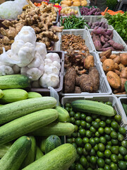 A colorful assortment of root vegetables, chilies, and leafy greens on display at a traditional farmer's market stall.