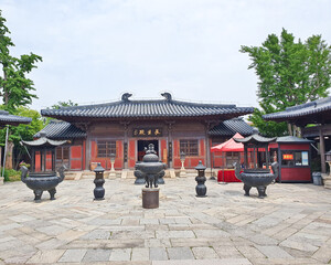 Traditional Chinese temple with red lanterns, stone incense burner, and calligraphy plaque,...